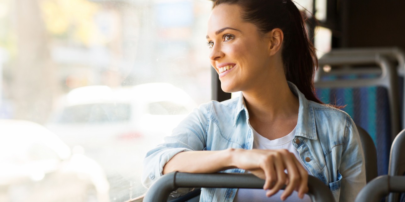 woman riding public transportation smiling and looking out the window.