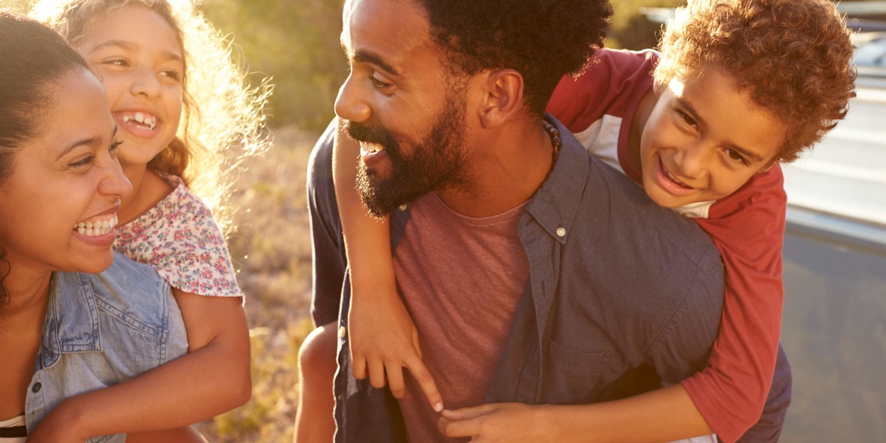 mother and father playing piggyback with daughter and son smiling