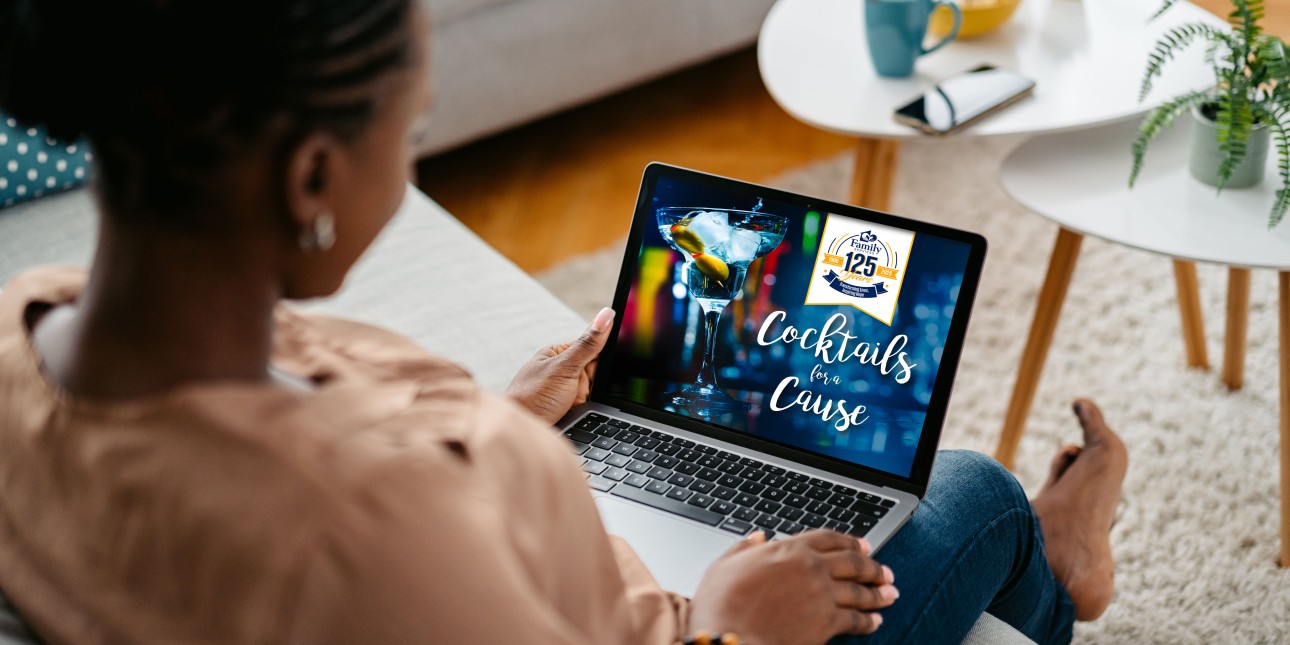 Looking over shoulder of woman sitting on a couch with a laptop on her lap