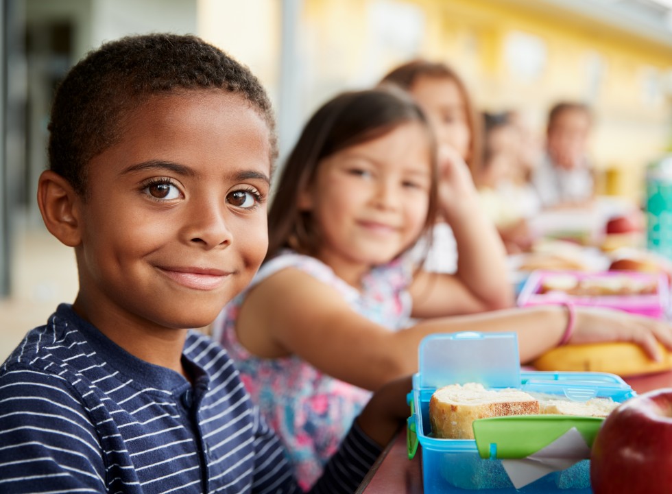 children sitting and smiling eating their lunch at school